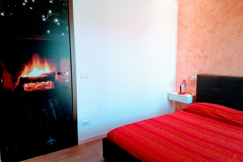 Holzfeuer im gemütlichen Schlafzimmer mit Kunst und Fernseher.