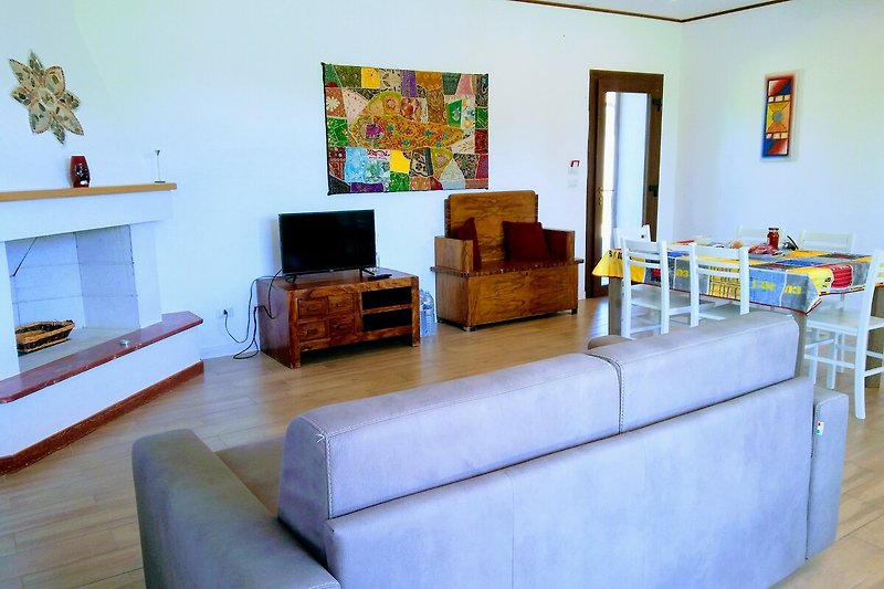 Wohnzimmer mit bequemer Couch, Pflanzen und Fernseher.