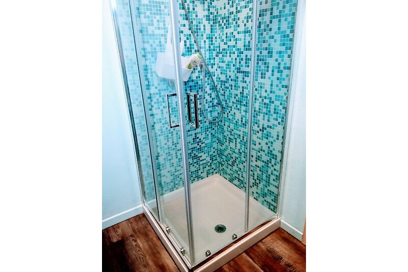 Blaues Badezimmer mit Glasdusche und Holzdetails.
