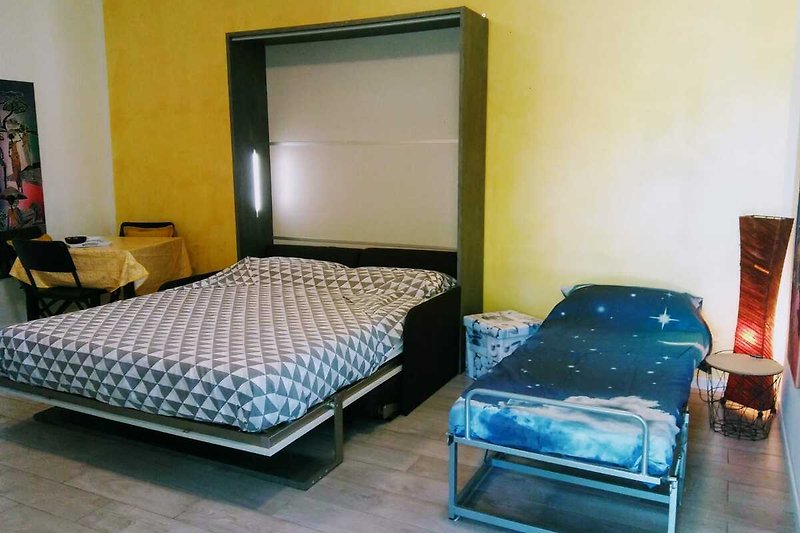 Schlafzimmer mit bequemem Bett, Holzmöbeln und blauer Decke.