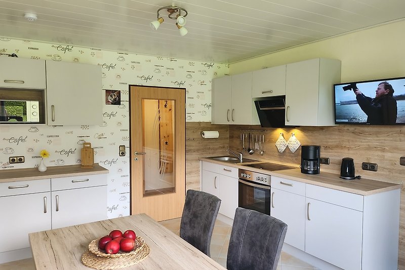 Die Küche mit separater Essecke im Landhausstil mit Vollaustattung und eigenen TV. Direkter Zugang zum Panoramabalkon.