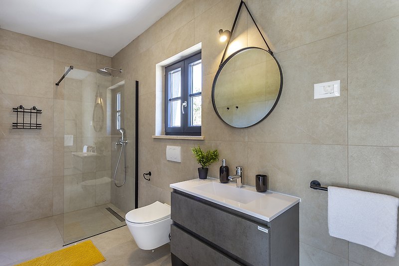 Moderan dizajn kupaonice s ogledalom, umivaonikom i tušem.