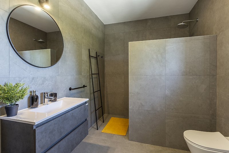 Moderan interijer kupaonice s ogledalom, umivaonikom i tušem
