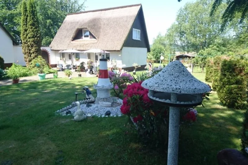 Großer Garten mit Reetdachhaus, viel Grün und bequemen Gartenmöbeln. Zeit zum Entspannen.