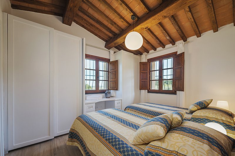 Gemütliches Schlafzimmer mit Holzbalken, Bett und Fenster.