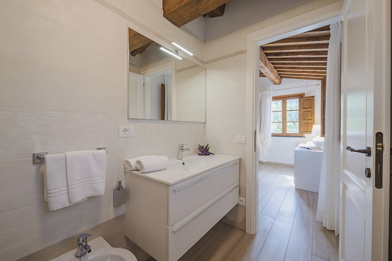 Elegantes Badezimmer mit Holzmöbeln, Spiegel und Badewanne.