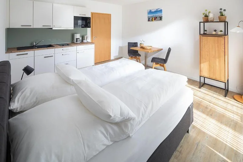 Komfortables Bett mit frischer Bettwäsche, Nachttisch und Lampe.