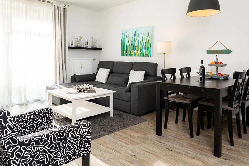 Großzügiger Wohnbereich mit Sofa, Couchtisch, Fernseher und Leuchte.