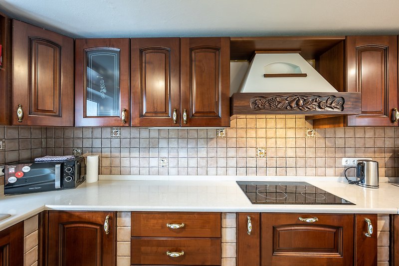 Schöne Küche mit braunen Schränken, weißer Arbeitsplatte und blauer Beleuchtung.