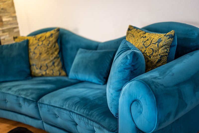 Gemütliches Wohnzimmer mit blauem Sofa und kreativen Kissen.