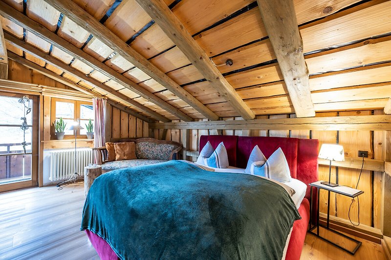 Gemütliches Schlafzimmer mit Holzbalken und bequemem Bett.