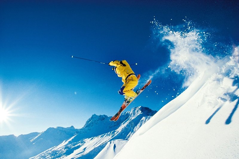 Winterlandschaft mit Skifahrern und schneebedeckten Bergen.