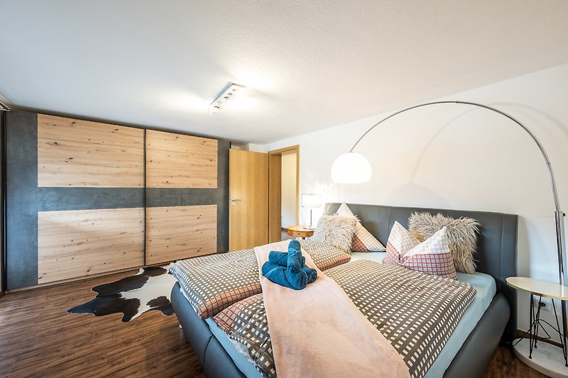 Gemütliches Schlafzimmer mit Holzbett, Fenster und Nachttisch.