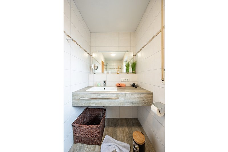 Gemütliches Badezimmer mit Holzboden, Keramikwaschbecken und modernen Armaturen.