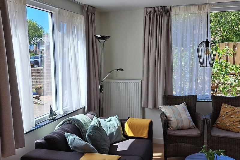 Wohnzimmer mit Couch, Kissen, Tagesbett und Zimmerpflanze.