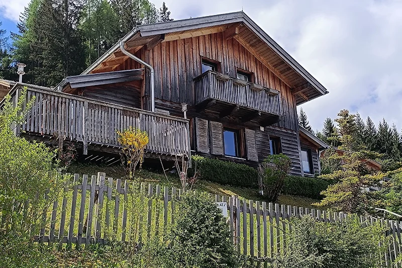 Traditionelles Holzhaus mit Satteldach und Terrasse rund um das Haus