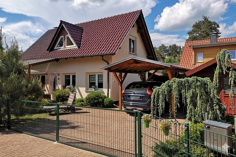 Außenansicht vom Ferienhaus mit Einfahrt, Vorgarten und Carport.