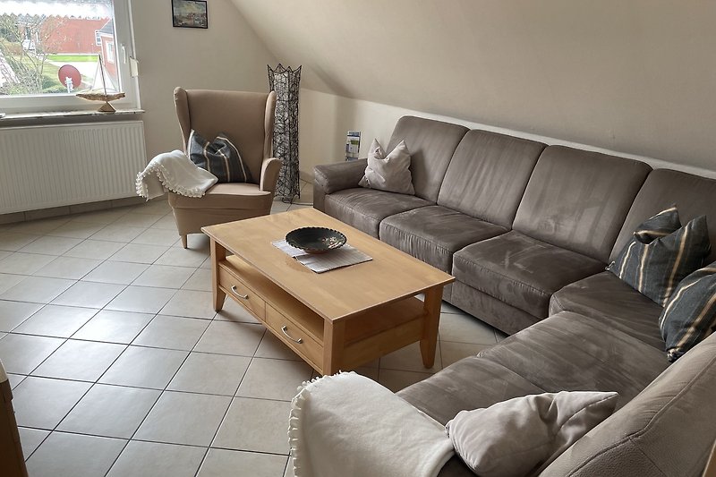 Wohnzimmer mit bequemer Couch, TV und Tisch.