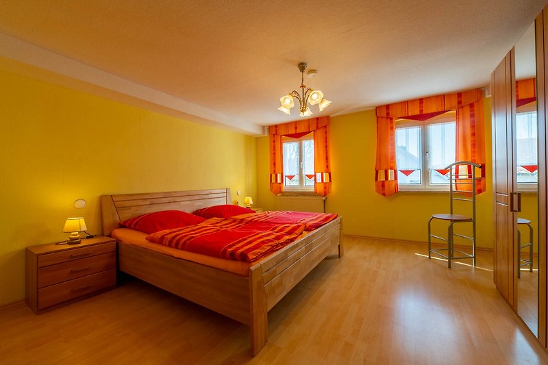 Schlafzimmer 2 Gemütliches Schlafzimmer mit Holzmöbeln und orangefarbenem Licht.