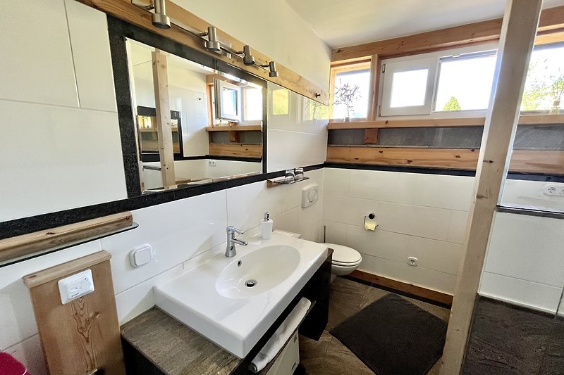 Ein modernes Badezimmer mit Spiegel, Waschbecken und Fenster.