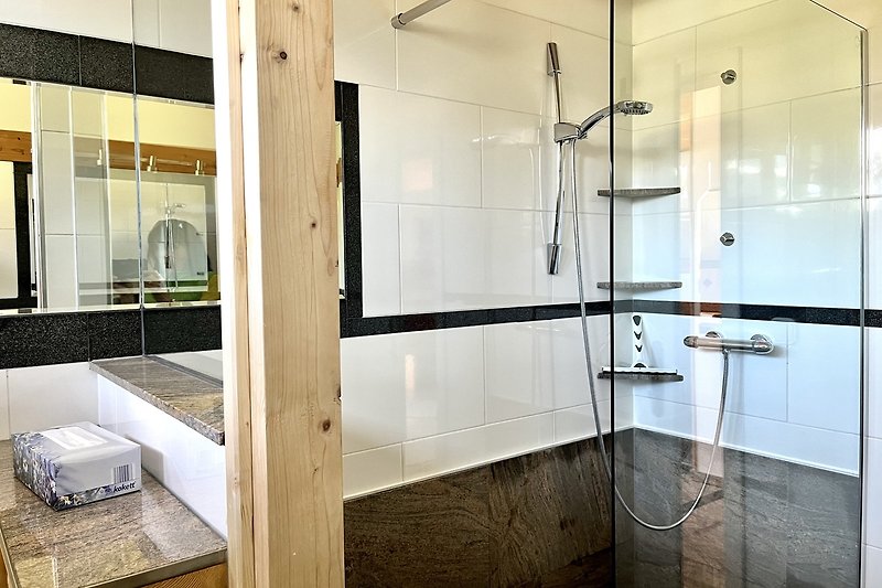 Ein modernes Badezimmer mit Glasdusche und Holzboden.