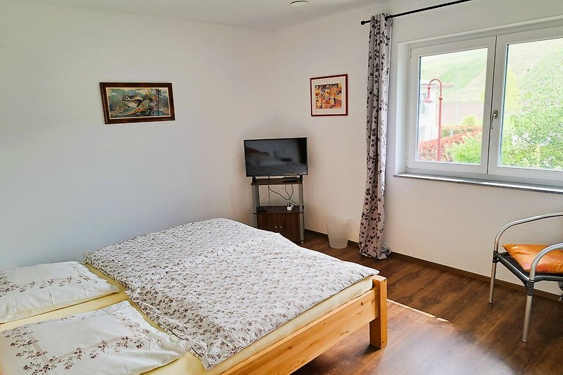 Gemütliches Schlafzimmer mit Bett, Fenster und Pflanze.