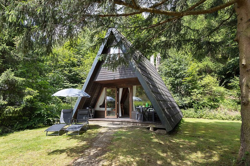 Gemütliche Hütte im Wald mit Garten und schattiger Terrasse.