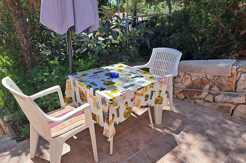 A2 Studio Eine idyllische Terrasse mit Möbeln, Sonnenschirm und Blick auf den Garten.