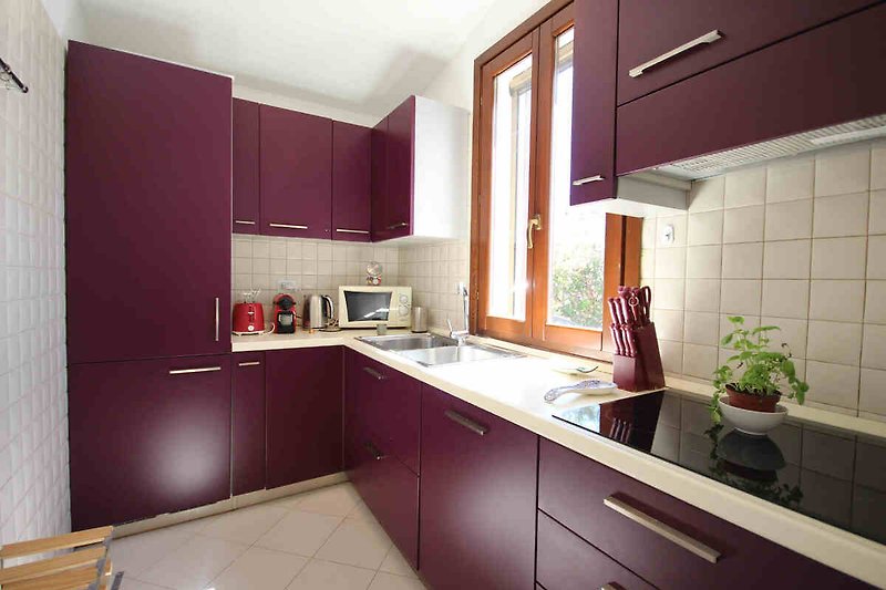 Moderne Küche mit lila Schränken, Holzarbeitsplatte und stilvoller Einrichtung.