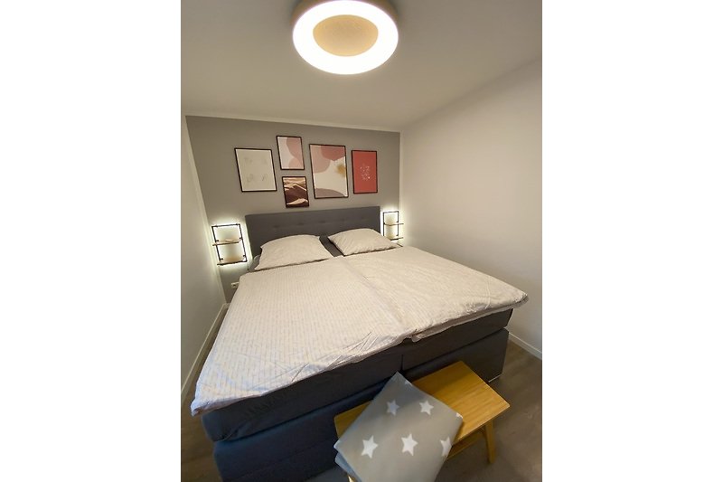 Schlafzimmer 3 mit gemütlichem Boxspring-Bett, Holzmöbeln und stimmungsvoller Beleuchtung.