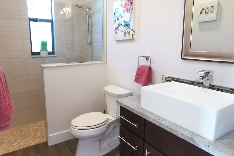 Gemütliches Badezimmer mit lila Waschbecken und Holzschrank.