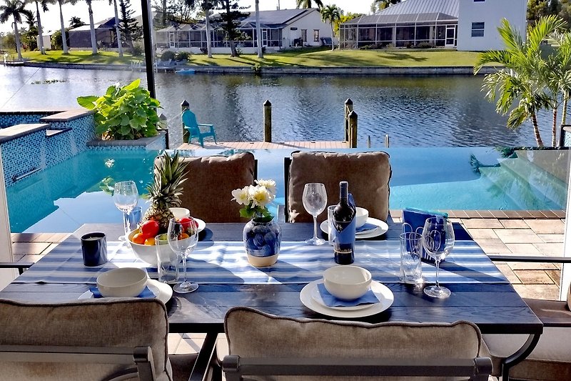 Rent this beautiful property with a stunning view of the water, outdoor furniture, and elegant tableware.