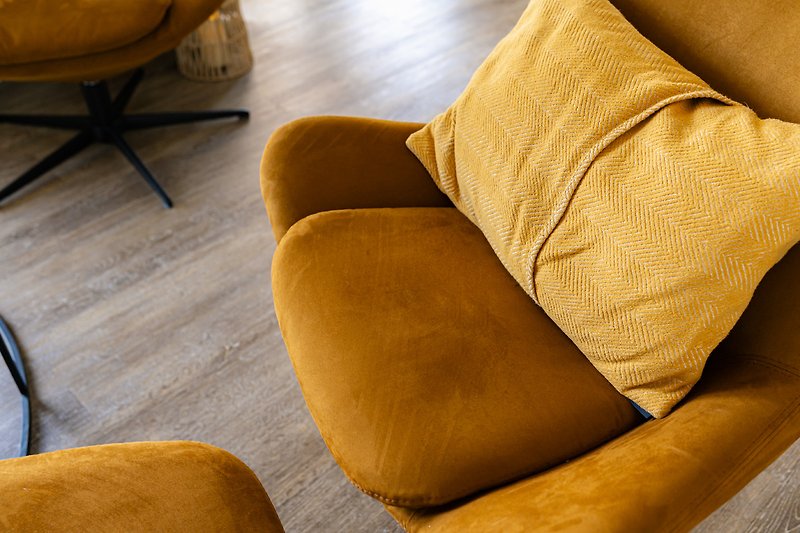 Gemütliche Couch mit orangefarbenem Kissen und Armlehne.
