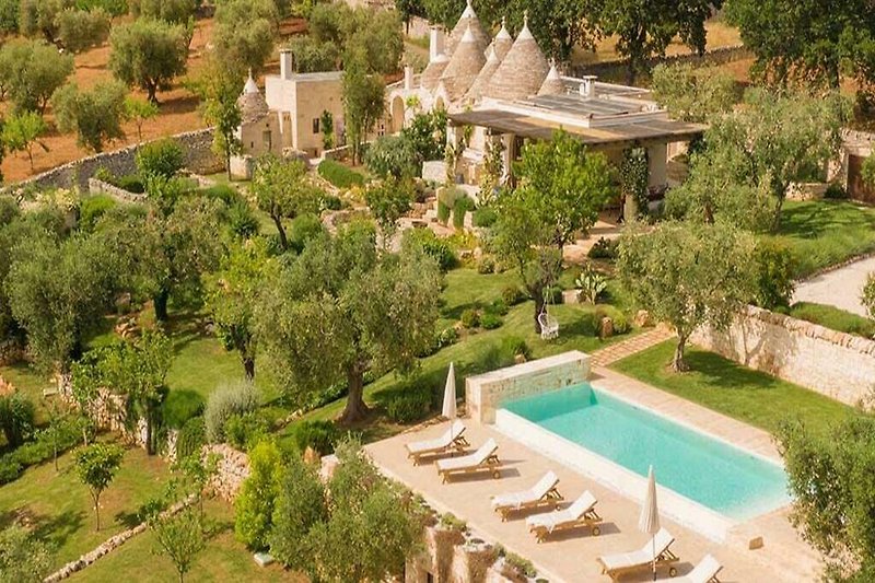 Luxuriöse Villa mit Pool, umgeben von üppiger Natur und Gärten.