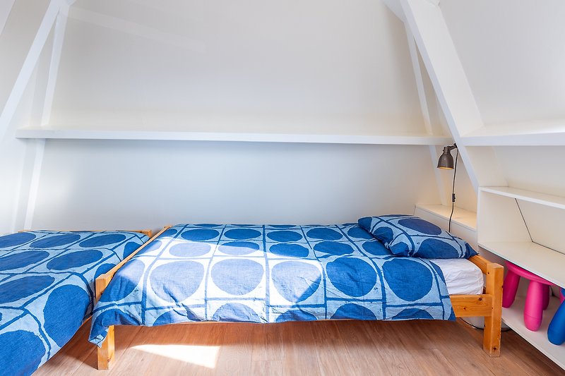 Comfortabele slaapkamer met houten meubels en een blauwe tint.