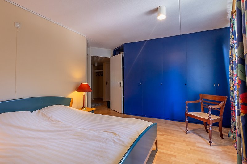 Comfortabele slaapkamer met blauwe tinten en houten meubels.