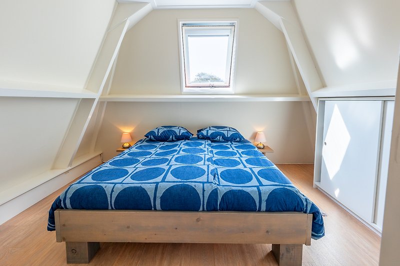 Comfortabele slaapkamer met houten meubels en een blauwe tint.