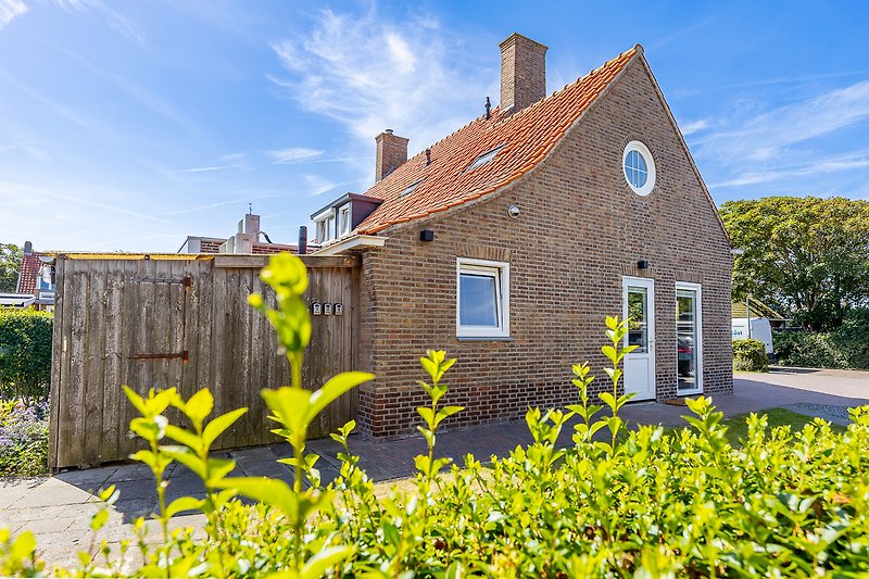 Charmantes Landhaus mit Garten, Bäumen und weitem Feld.