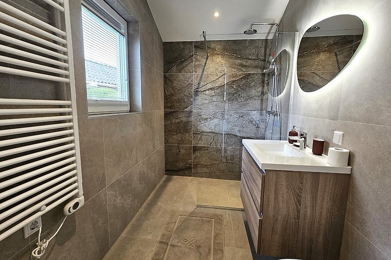 Badezimmer mit Spiegel, Waschbecken und Dusche. Gemütliche Beleuchtung.