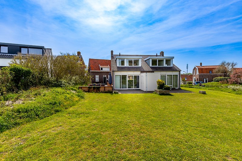 Ländliches Haus mit grünem Garten und blauem Himmel.