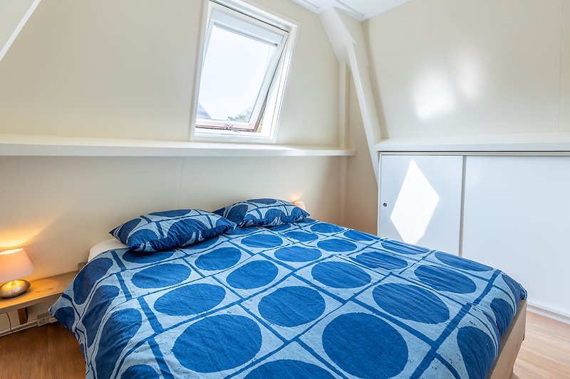Comfortabele slaapkamer met houten bed en blauwe tint.