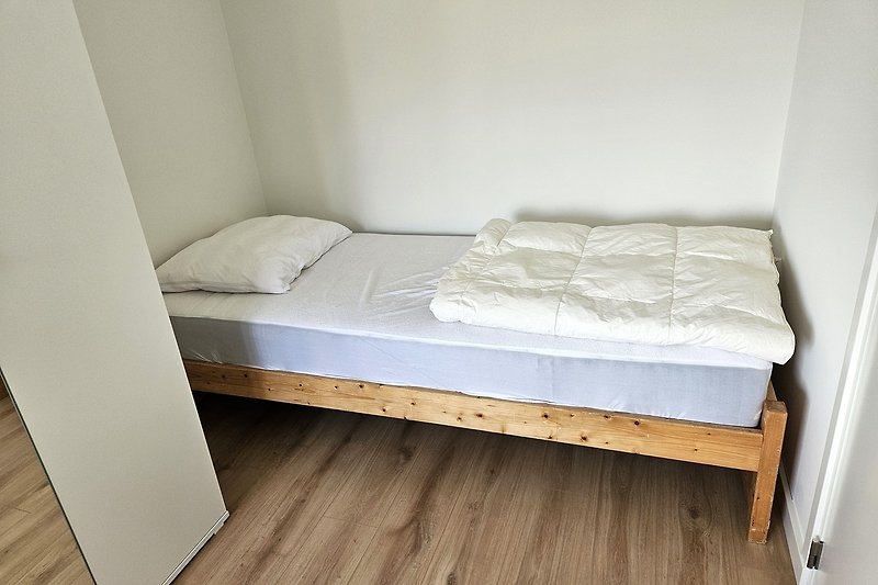 Schlafzimmer mit gemütlichem Bett und Holzboden.