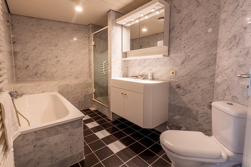 Prachtige badkamer met een zwarte en paarse inrichting, houten vloer en glazen douchewand.