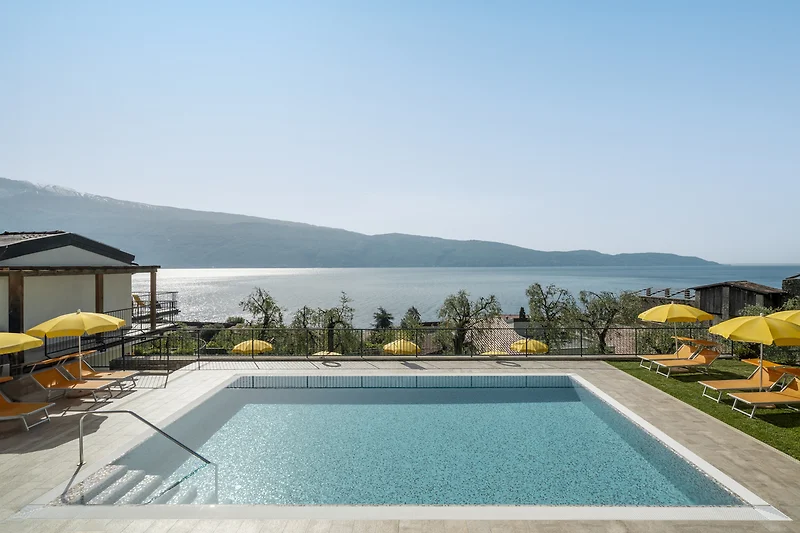 Öko-Resort mit Pool, Sonnenliegen, Schirmen und tropischen Pflanzen.