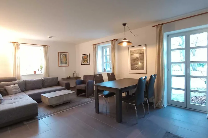 Wohnbereich mit Sofa, Esstisch und Ausgang zur Terrasse