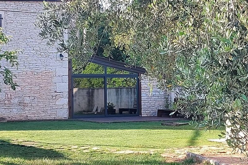 Schönes Landhaus mit grünem Garten und schattigem Olivenbaum.