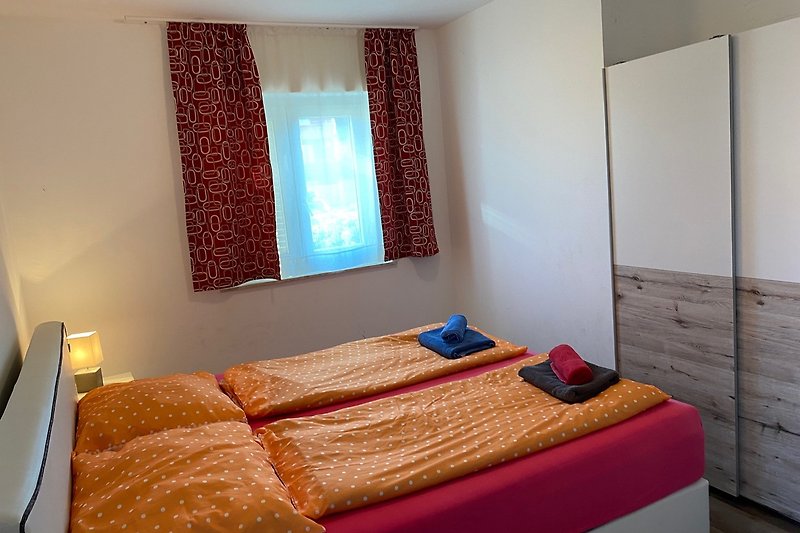 Schlafzimmer mit großem Doppelbett, Fenster und kleinem Balkon