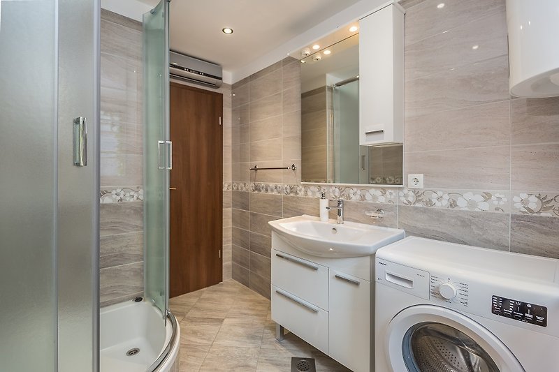 Prekrasna kupaonica s ogledalom, umivaonikom i modernim slavinama.