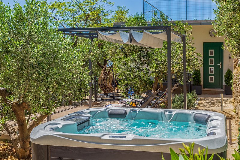 Privater Pool mit Jacuzzi, umgeben von Pflanzen und Holzterrasse.