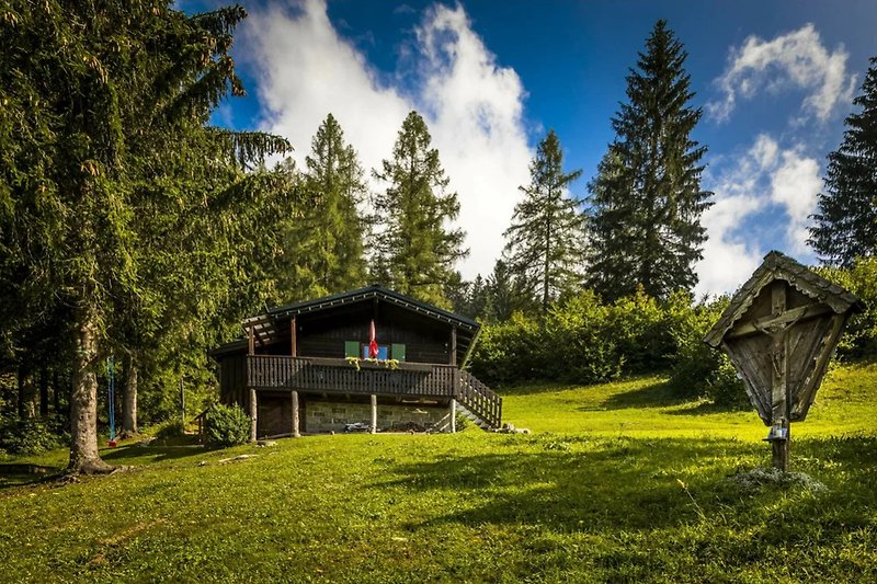 Ferienhaus in den Bergen mit grüner Landschaft und Hütte.